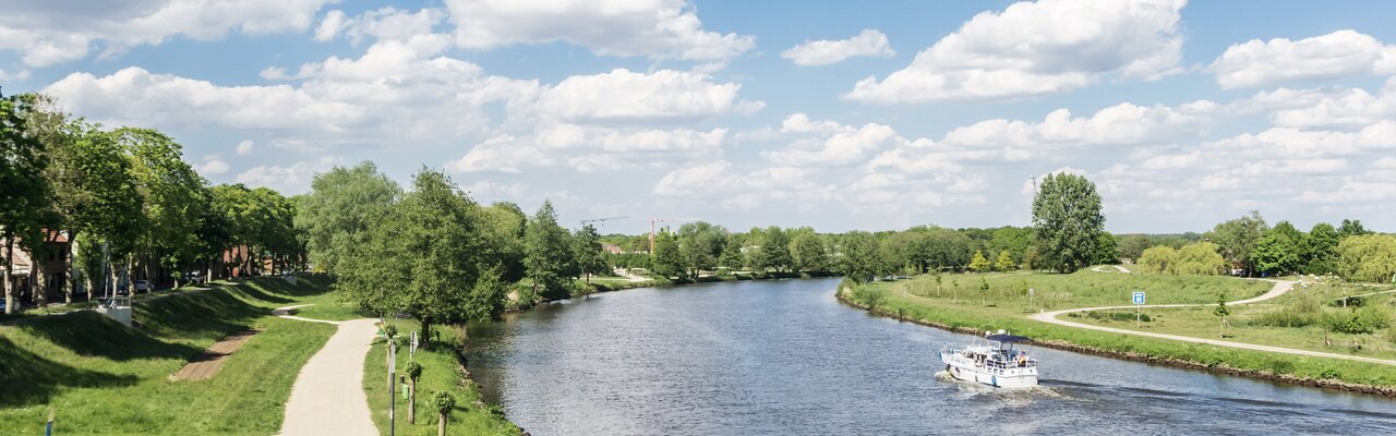 Die Ems bei Haren | © Bildlizenzen von Shutterstock.com Flusskurve der Ems mit weißem Schiff neben Radweg bei Haren | © Bildlizenzen von Shutterstock.com