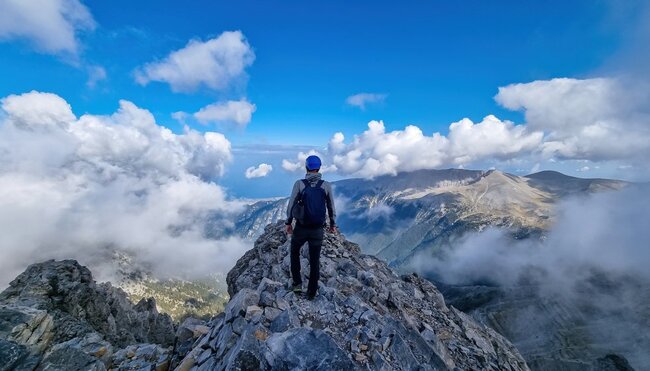 Rückansicht eines Mannes auf dem wolkenbedeckten Berggipfel des Mytikas Olymp
