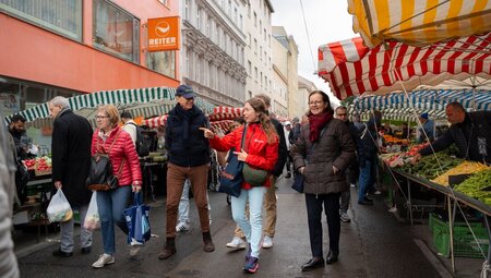 Leader walking with travellers in a market in Vienna, Austria