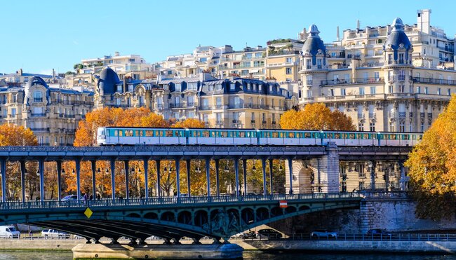 Train over the River Seine in Paris in autumn with classic architecture and bright orange trees