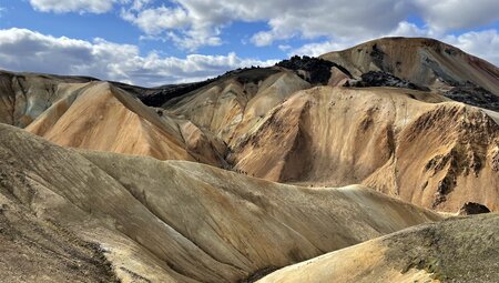 Intrepid travellers hike down a long volcanic soil ridge in the landscape of Iceland