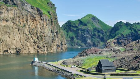 Wide view of Westman Island in Iceland, surrounded by water and green rock side