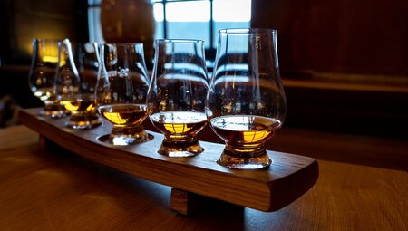 Four whisky tasting glasses lined up in a dimly lit pub in Edinburgh, Scotland