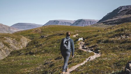 Male traveller hikes toward plateau mountain tops in western Greenland toward Lingmark Glacier
