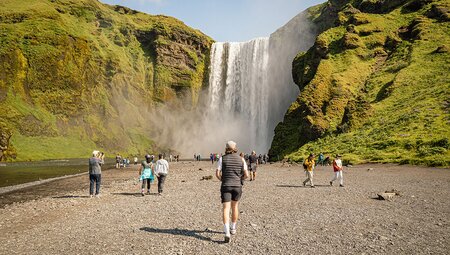 Group walks toward Skógafoss waterfall