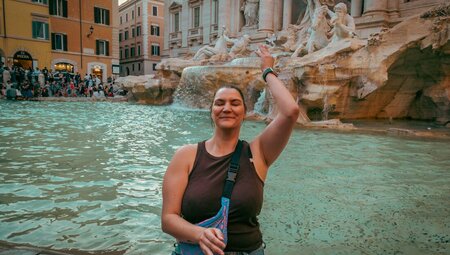 Traveller Rachael Sarra throwing a coin into Trevi fountain in Rome in the evening