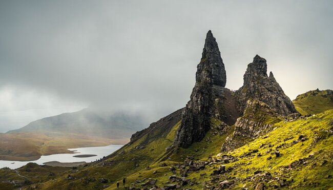 Travellers look up at the towering Old Man of Storr on the Isle of Skye in Scotland