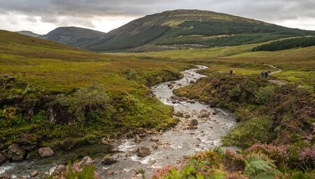 Isle of Skye landscape with a winding river cutting through glens and low mountains beyond in Scotland