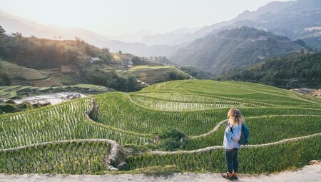 Intrepid traveller on a path taking in the carved hills of Sapa's rice terraces in north Vietnam