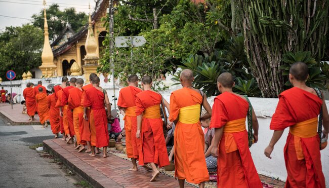 Buddhist monks walk through Luang Prabang with special buckets for alms in Laos