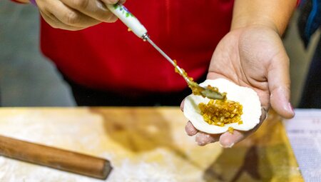 Close shot of Intrepid leader holding an open dumpling with fresh filling in China