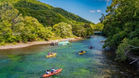 Group of travellers in double canoes row into Lake Shikotsu