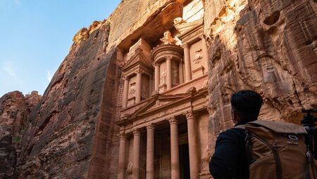 Intrepid traveller looks up the detailed carved stone facade of Al-Khazneh in Petra, Jordan