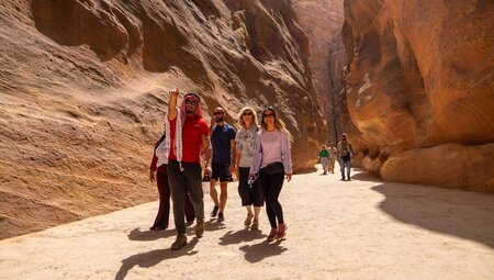 Group led by Intrepid leader hiking in Petra as they approach Al-Khazneh in Jordan