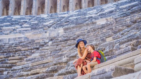 Mother and son relax on the stione seats of an ancient ampitheater in Antalya