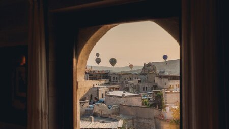 Hot air balloons go up with the sunrise seen from accomodation in Cappadocia in Turkey