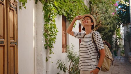 Traveller in the streets of Marmaris looks up at old buildings covered in ivy vines in Turkish riviera