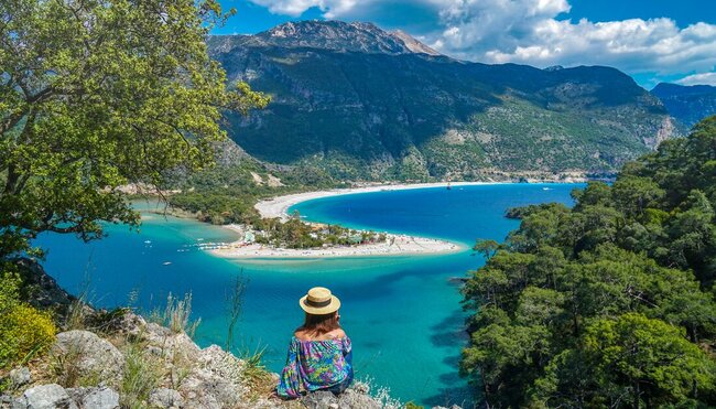 Woman stops on walk on the coast of Turkey to look at penninsula of Fethiye town