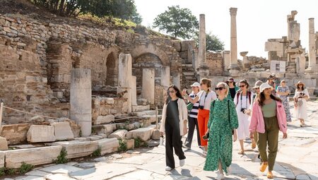Womens expedition travellers walking on stone path through ruins of Ephesus