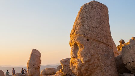Ancient statue heads of kings and gods lit by the setting sun on the summit of Mount Nemrut in eastern Turkey