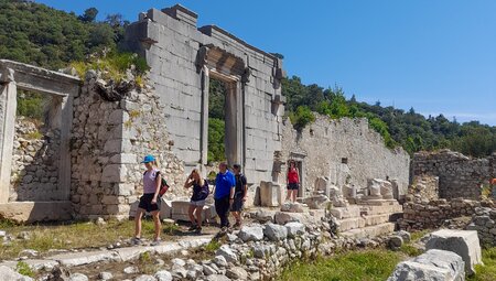 Intrepid travellers walk past ruins on the hike along the Lycian Way in Turkey