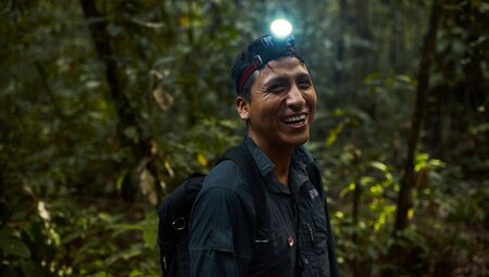 Intrepid leader with headlamp laughs with joy on night walk in the Amazon Peru