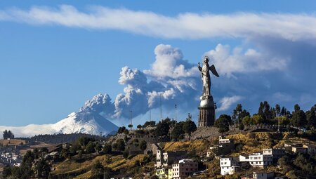 Panecillo's Madonna statue in Quito with Cotopaxi Volcano erupting in the background, Ecuador