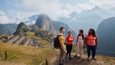 Intrepid travellers talk and laught together at the Machu Picchu lookout in Peru