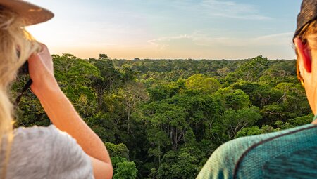 Intrepid travellers look out at the Amazon Rainforest at sunset in Puerto Maldonado