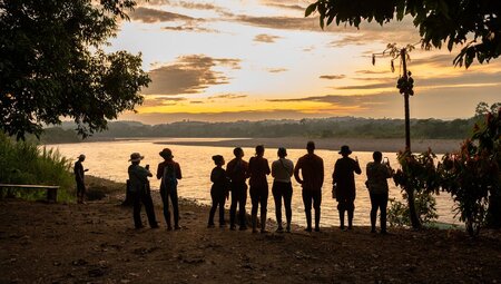 Travellers looking out over the amazon rainforest and river at sunset
