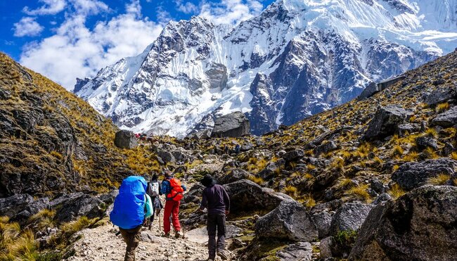 Travellers trekking towards snowcapped mountain Salkantay insight, along the Andes ranges in Peru