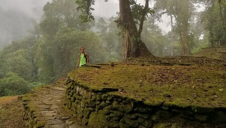 Traveller looks around a Ciudad Perdida terrace on a misty morning in the Sierra Nevada mountains in Colombia
