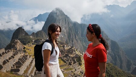 Traveller and leader stop and smile at the lookout of Machu Picchu