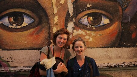 Travellers pose in front of street art of eyes in the streets of Buenos Aires in Argentina