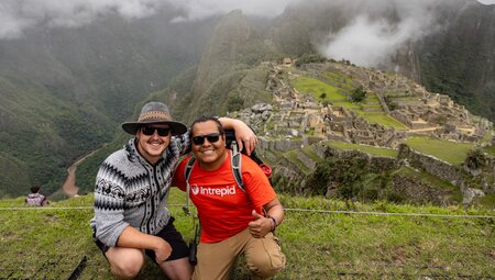 Leader and traveller at summit posing with Machu Picchu in background