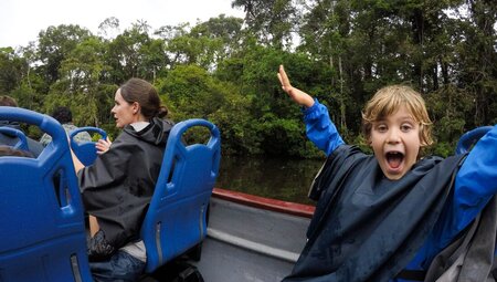 Happy son on family boat cruise in Amazon Rainforest, Ecuador