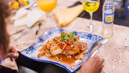 Traveller looks at a beautifully presented meal on an undulating plate with Peruvian cola at the end of the Inca Trail