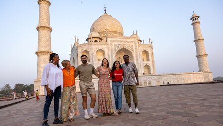 Travellers gather for a group shot in front of the Taj Mahal in the early morning light in Rajasthan