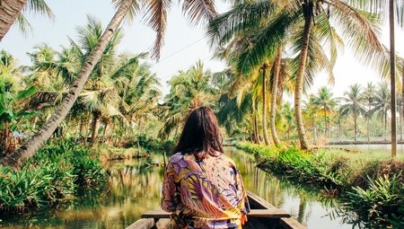 Traveller cruising on small river boat in Kerala Backwaters in southern India