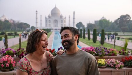 Two travellers laugh together standing in front of the Taj Mahal near Agra India