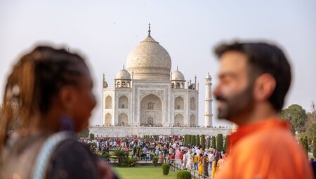 Travellers smile and laugh with each other looking out at the Taj Mahal in Agra