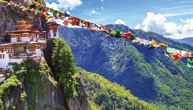 HEPIC - View of the Tiger Monastery and colourful flags on a hill in Bhutan