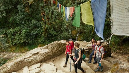 Travellers hike under prayer flags in Ghorepani, Nepal