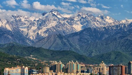 Alatau mountains rise high with snow caps behind Almaty buildings in Kazakhstan