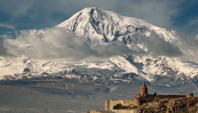 Wide view with Khor Virap Monastery buildings in foreground with Mount Ararat looming beyond