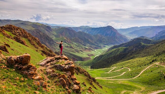 Intrepid traveller stops for a lookout while trekking in the Tien Shan Mountains of Kyrgyzstan