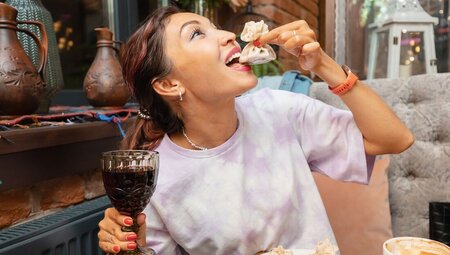 Traveller posing for photo with traditional khinkali dumpling with glass of wine in Georgia