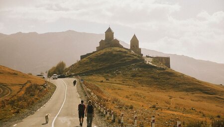 Intrepid travellers and leader walking to a monastery outside Gudauri, Georgia