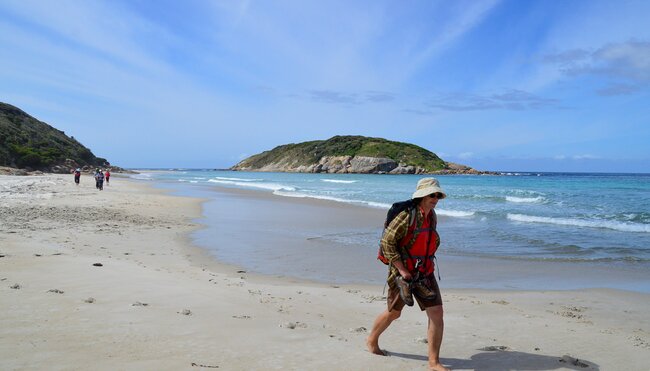 Intrepid traveller with hiking gear takes a barefoot walk along a beach on the Bibbulmun Track