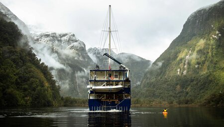 Clouds roll down from the peaks of Doubtful Sound as the Fjordland Navigator sails through in New Zealand